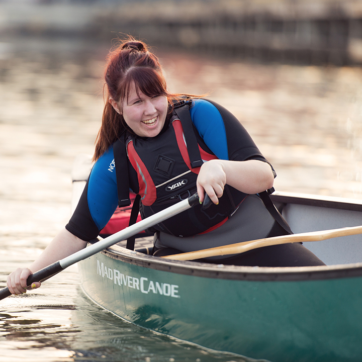 Smiling teenage girl rowing a boat